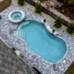 Lux Project 14 custom oasis pool with integrated spa, surrounded by waterfalls and a fireplace