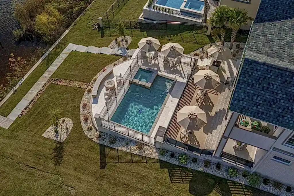 Lux Project 10 featuring a custom rectangular pool and spa with a waterfall feature, accompanied by a stylish custom fireplace