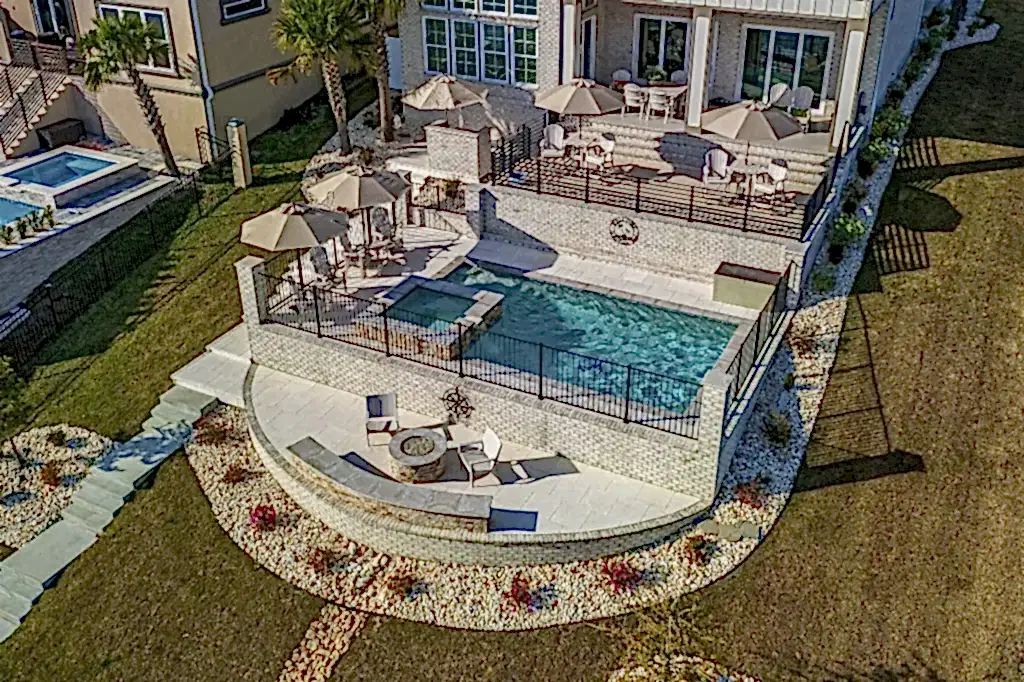 Lux Project 10 featuring a custom rectangular pool and spa with a waterfall feature, accompanied by a stylish custom fireplace