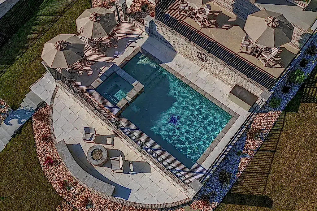 Lux Project 10 featuring a custom rectangular pool and spa with a waterfall feature, accompanied by a stylish custom fireplace